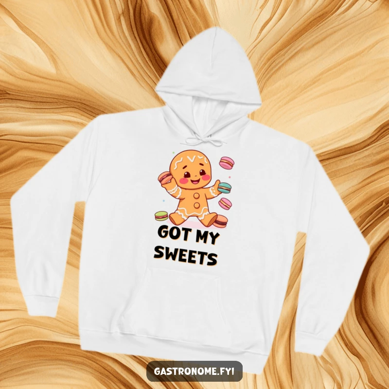 Funny gingerbread man juggling colorful macarons, depicted on a warm and cozy hoodie, ideal for a humorous and sweet present.
